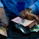 a-bank-teller-counts-money-while-serving-customers-at-bank-of-kigali-head-office.-dan-nsengiyumva-