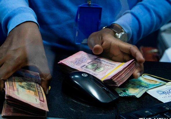 a-bank-teller-counts-money-while-serving-customers-at-bank-of-kigali-head-office.-dan-nsengiyumva-